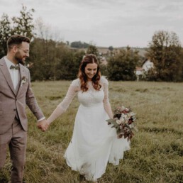 Glücklicher Bräutigam lächelt seine Braut an und Hochzeitsfotografin Martina Feicht fotografiert sie