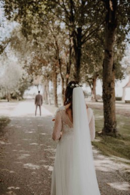 Die Braut kommt zum First Look in ihren weißen Hochzeitskleid und wird gleich zum ersten mal auf ihren Bräutigam treffen