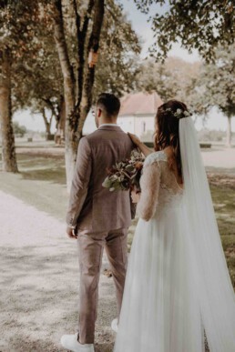 Braut steht hinter Bräutigam und bittet ihn sich umzudrehen in ihrem Hochzeitskleid fotografiert von Martina Feicht