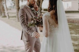 Braut steht hinter Bräutigam und bittet ihn sich umzudrehen in ihrem Hochzeitskleid fotografiert von Martina Feicht