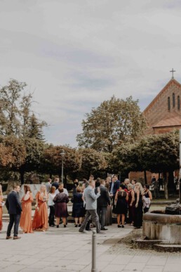 Hochzeitsgäste warten vor der Kirche in Passau auf das Brautpaar und werden von Martina Feicht fotografiert