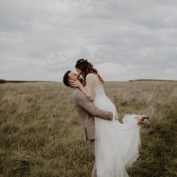 Glücklicher Bräutigam lächelt seine Braut an und Hochzeitsfotografin Martina Feicht fotografiert sie