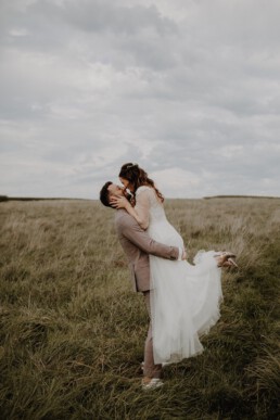 Glücklicher Bräutigam lächelt seine Braut an und Hochzeitsfotografin Martina Feicht fotografiert sie