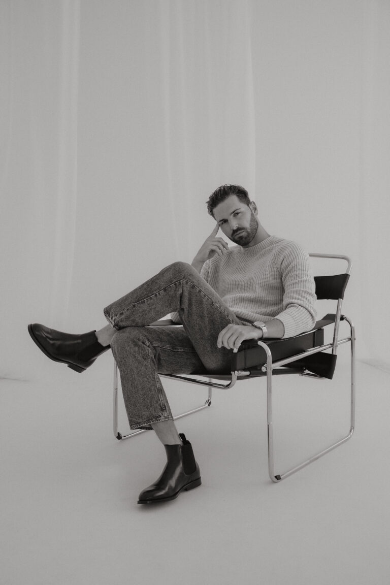 Mann sitzt entspannt auf einem Designerstuhl, Schwarz-Weiß